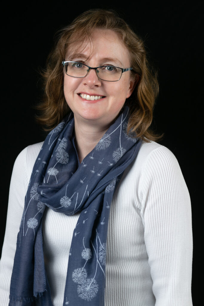 Picture of Hannah, with a cream top and blue scarf